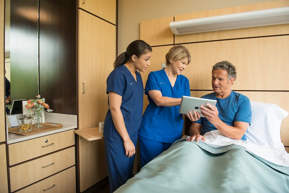 Two nurses and a patient looking at a tablet